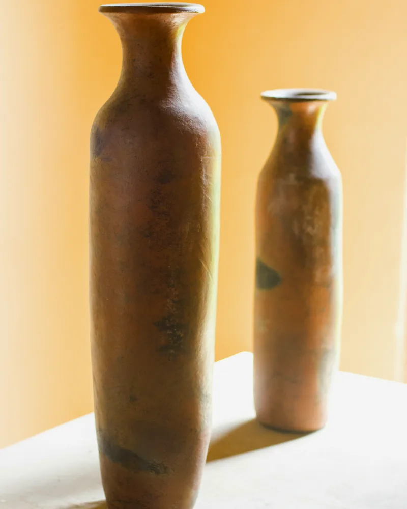 Two tall hand-finished ceramic vessels in warm studio light