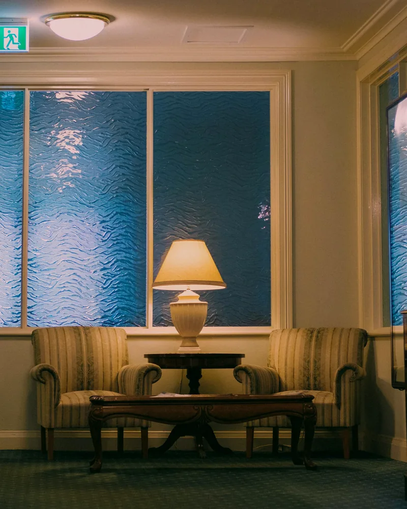 Moody blue-toned lounge with low seating and a glowing table lamp