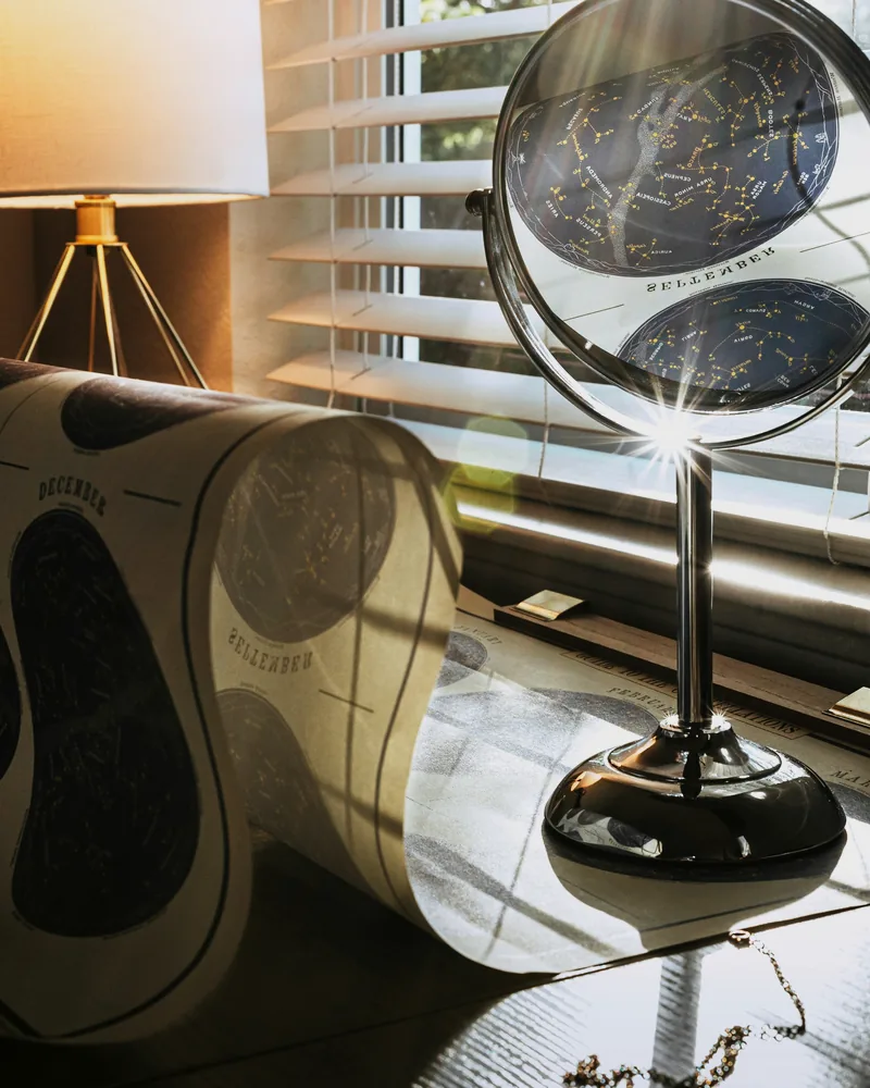 Reflective sculptural mirror and lamp forms beside a sunlit window